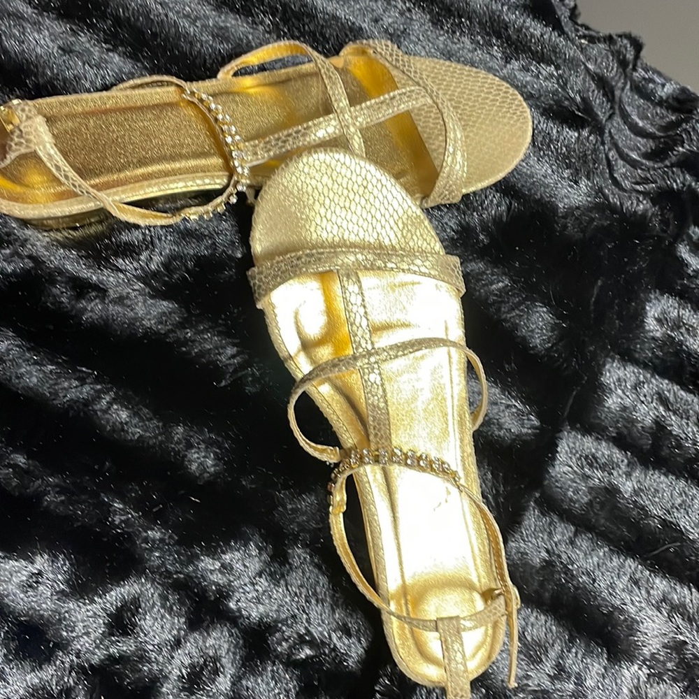 Gold sandal with adjustable strap around ankle. Flats brand name not available
